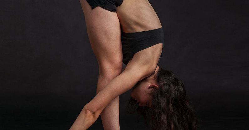 Yoga Skin - Woman Wearing Black Sports Bra Reaching Floor While Standing