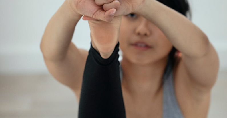 Holistic Wellness - Focused flexible ethnic female stretching legs and practicing yoga in Navasana on mat at home