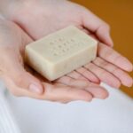 Dry Shampoo - Crop anonymous female showing rectangular shaped dry ecological shampoo with title on blurred background