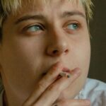 Microneedling Face - A young man with blonde hair smoking a cigarette