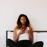 Cosmetic Technology - Woman using phone while sitting on bed