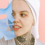 Tattoo Removal - Young woman in towel on head removing mask from face