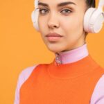 Beauty Gadgets - Woman in Orange and Pink Turtle Neck Shirt Holding Black Smartphone