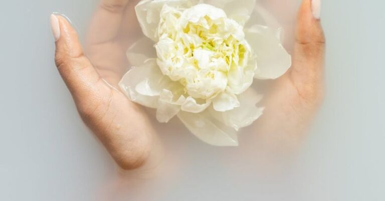 LED Therapy - Unrecognizable female with soft manicured hands holding white flower with delicate petals in hands during spa procedures